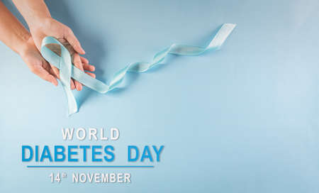 World diabetes day awareness concept. Hand holding blue ribbon, symbolic bow color raising awareness in diabetes day on pastel background,  14 November.の写真素材