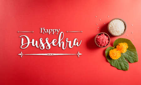 Happy Dussehra. Yellow flowers, green leaf and rice on red background. Dussehra Indian Festival concept.の写真素材