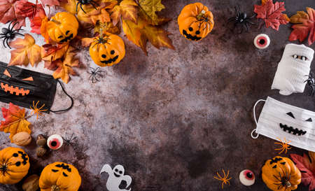 Halloween decorations made from pumpkin, paper bats,medical mask and black spider on dark stone background. Flat lay, top view with copy space for text.の写真素材
