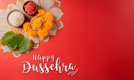 Happy Dussehra. Yellow flowers, green leaf and rice on red background. Dussehra Indian Festival concept.の写真素材