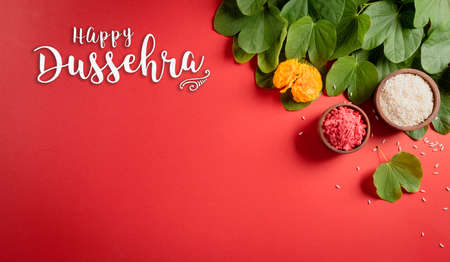 Happy Dussehra. Yellow flowers, green leaf and rice on red background. Dussehra Indian Festival concept.の写真素材