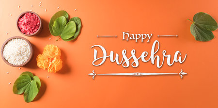 Happy Dussehra. Yellow flowers, green leaf and rice on orange background. Dussehra Indian Festival concept.の写真素材