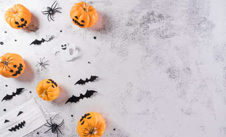 Halloween decorations made from pumpkin, paper bats, medical mask and black spider on stone background. Flat lay, top view with copy space for text.の写真素材