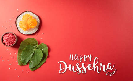 Happy Dussehra. Yellow flowers, green leaf and rice on red background. Dussehra Indian Festival concept.の写真素材