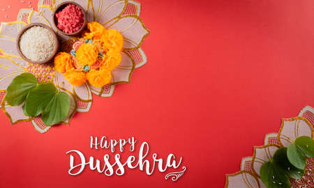 Happy Dussehra. Yellow flowers, green leaf and rice on red background. Dussehra Indian Festival concept.の写真素材