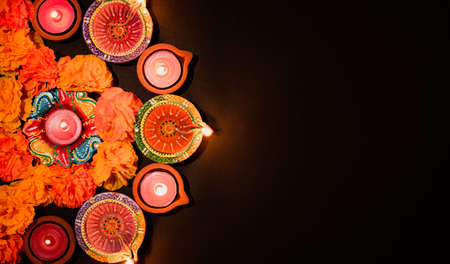 Happy Diwali - Clay Diya lamps lit during Dipavali, Hindu festival of lights celebration. Colorful traditional oil lamp diya on black backgroundの写真素材