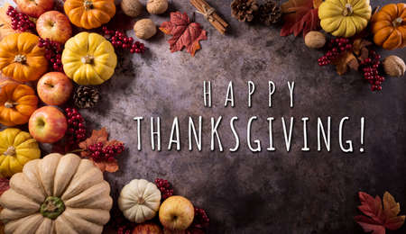 Thanksgiving background concept with fall leaves, pumpkin and seasonal autumnal decor on dark stone background.の写真素材