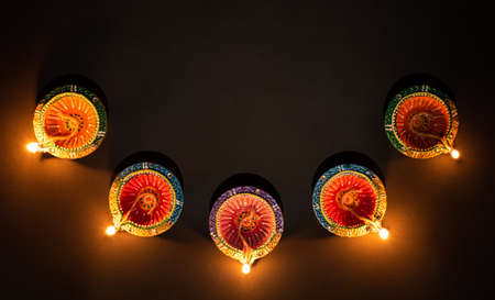 Happy Diwali - Clay Diya lamps lit during Dipavali, Hindu festival of lights celebration. Colorful traditional oil lamp diya on black backgroundの写真素材