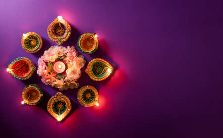 Happy Diwali - Clay Diya lamps lit during Dipavali, Hindu festival of lights celebration. Colorful traditional oil lamp diya on purple backgroundの写真素材