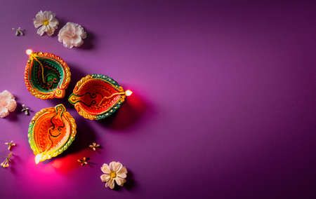 Happy Diwali - Clay Diya lamps lit during Dipavali, Hindu festival of lights celebration. Colorful traditional oil lamp diya on purple backgroundの写真素材