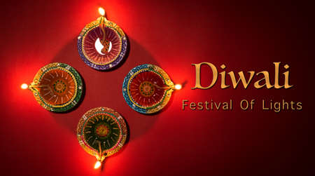 Happy Diwali - Clay Diya lamps lit during Dipavali, Hindu festival of lights celebration. Colorful traditional oil lamp diya on red 
backgroundの写真素材