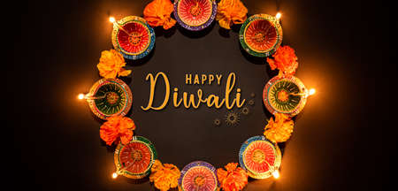 Happy Diwali - Clay Diya lamps lit during Dipavali, Hindu festival of lights celebration. Colorful traditional oil lamp diya on black backgroundの写真素材