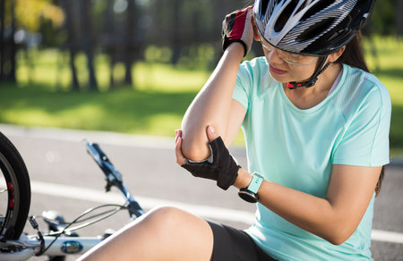 Bike injuries. Woman cyclist fell off road bike while cycling. Bicycle accident, injured back.の写真素材