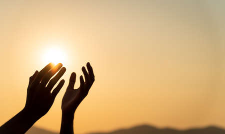 Closeup woman hands praying for blessing from god during sunset background. Hope and freedom concept.の写真素材