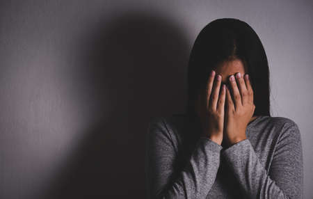 Sad woman close her face and cry. Sad woman sitting alone in a empty room.の写真素材