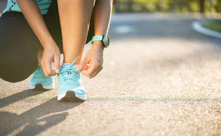 Running shoes - closeup of woman tying shoe laces. Female sport fitness runner getting ready for jogging in garden background.の写真素材