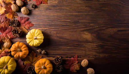 Autumn composition. Pumpkin, pine cone and autumn leaves on dark wooden background. Flat lay, top view with copy spaceの写真素材