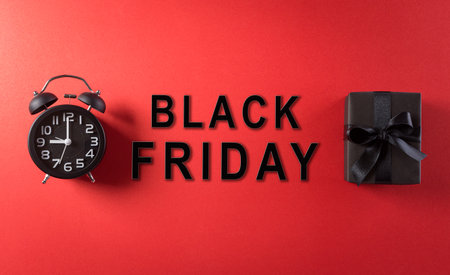 Top view of Black Friday Sale text with Alarm clock and gift box on red background. Shopping concept boxing day and Black Friday composition.の写真素材