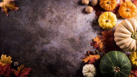 Thanksgiving background concept with fall leaves, pumpkin and seasonal autumnal decor on dark stone background.の写真素材