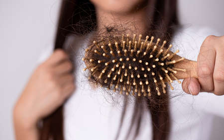 Healthy and hair loss concept. Woman holding a comb with her damaged long loss hair.の写真素材