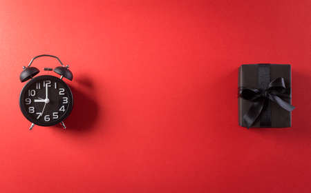 Top view of Black Friday Sale text with Alarm clock and gift box on red background. Shopping concept boxing day and Black Friday composition.の写真素材