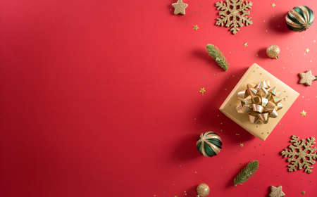 Christmas and new year background concept. Top view of Christmas decoration made from gift box, snowflake, christmas ball and  pine branches on red background.の写真素材