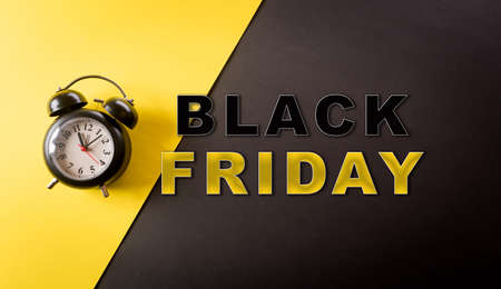 Top view of black alarm clock on yellow and black background. Shopping concept boxing day and Black Friday composition.の写真素材