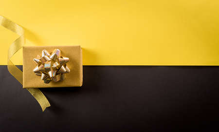 Top view of Black Friday Christmas gift box and golden ribbon on yellow and black background. Shopping concept boxing day and Black Friday composition.の写真素材