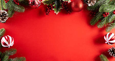 Christmas background concept. Top view of Christmas pine branches, pine cones, red berries star and bell on red background.の写真素材