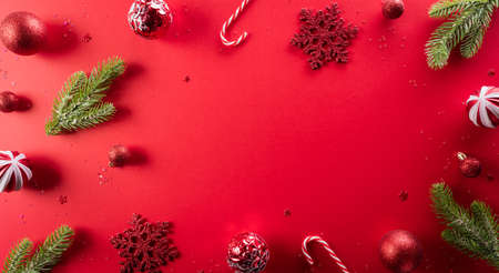 Christmas and new year background concept. Top view of Christmas pine branch, christmas ball and snowflake on red background.の写真素材