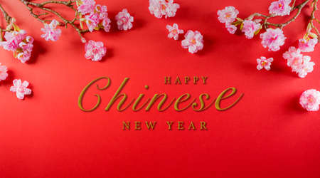 Chinese new year festival decorations made from plum blossom on a red background.  Flat lay, top view with the text.の写真素材