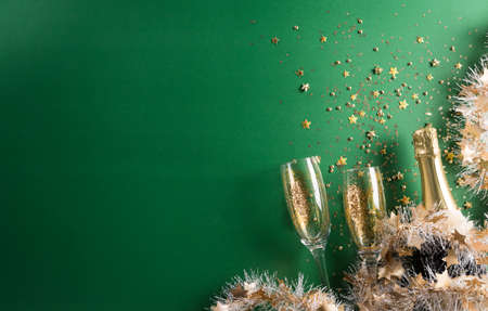 Happy New year celebration background concept. Champagne with glass, golden ribbon, stars and christmas ball on green background.の写真素材
