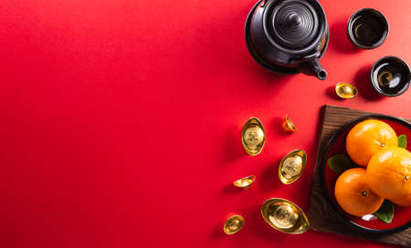 Chinese new year decorations made from red packet, orange and gold ingots or golden lump on a red background. Chinese characters FU in the article refer to fortune good luck, wealth, money flow.の写真素材