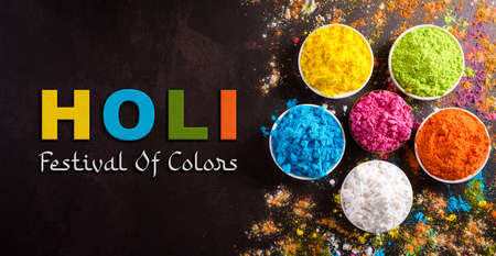 Happy holi festival decoration.Top view of colorful holi powder on dark background with the text.の写真素材