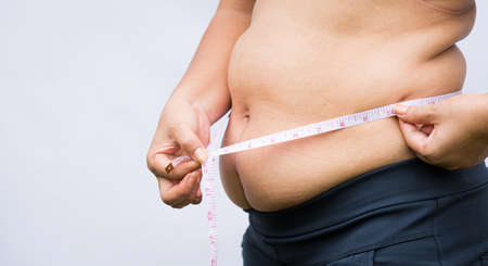 Fat woman holding excessive belly fat with measuring tape. Healthcare and woman diet lifestyle concept to reduce belly and shape up healthy stomach muscle.の写真素材