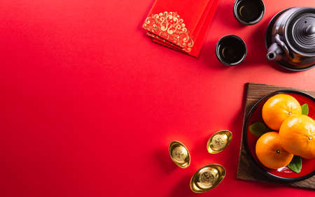 Chinese new year decorations made from red packet, orange and gold ingots or golden lump on a red background. Chinese characters FU in the article refer to fortune good luck, wealth, money flow.の写真素材