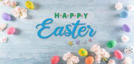 Happy easter! Colourful of easter eggs with flower and the text on pastel blue wooden background. Greetings and presents for Easter Day celebrate time.の写真素材