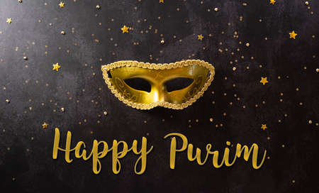 Happy Purim carnival decoration concept made from golden mask and sparkle star on dark background. (Happy Purim in Hebrew, jewish holiday celebrate)の写真素材