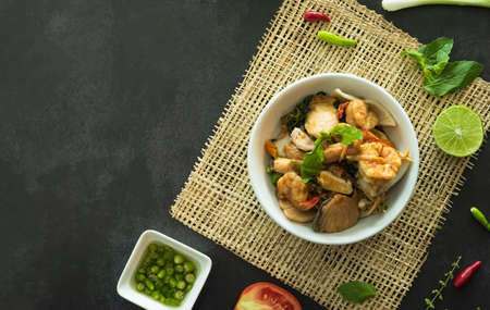 Top view of stir fried basil with seafood served in a bowl on dark stone background. A famous Thai street food.の写真素材