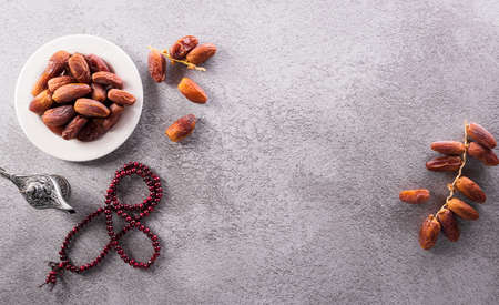 Top view image of Ramadan Kareem decoration, dates fruit, tea and rosary beads on dark stone background.の写真素材