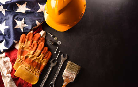 Happy Labor day concept. American flag with different construction tools on dark stone background.