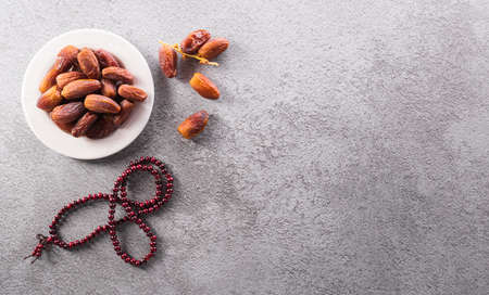 Top view image of Ramadan Kareem decoration, dates fruit and rosary beads on dark stone background.の写真素材