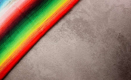 Cinco de Mayo holiday background made from mexican blanket stripes or poncho serape on dark stone...