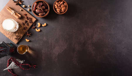 Table top view image of decoration Ramadan Kareem, dates fruit, aladdin lamp, milk and rosary beads on dark stone background. Flat lay with copy space.の写真素材