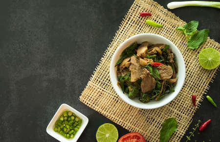 Top view of stir fried basil with duck served in a bowl on dark stone background. A famous Thai street food.の写真素材