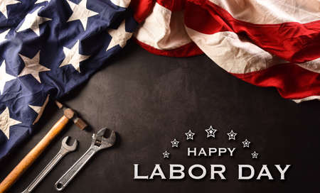 Happy Labor day concept. American flag with different construction tools and the text on dark stone background.の写真素材