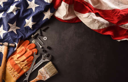 Happy Labor day concept. American flag with different construction tools on dark stone background.の写真素材