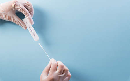 Close up doctor hand holding covid-19 rapid antigen test on blue background. Worldwide coronavirus epidemic concept.の写真素材