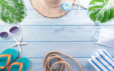 Summer composition concept made from starfish, beach hat, flip flop, airplane,medical mask and monstera leaf on pastel blue background.  Summer travel during covid-19 disease concept.の写真素材