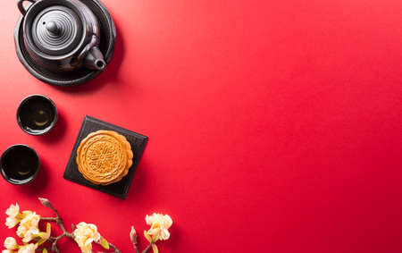Chinese Mid-Autumn Festival concept made from mooncakes, tea and plum blossom on red background.の写真素材